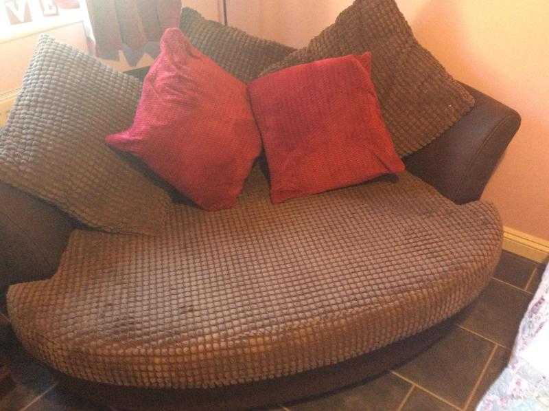 Brown round sofa with two red cushions