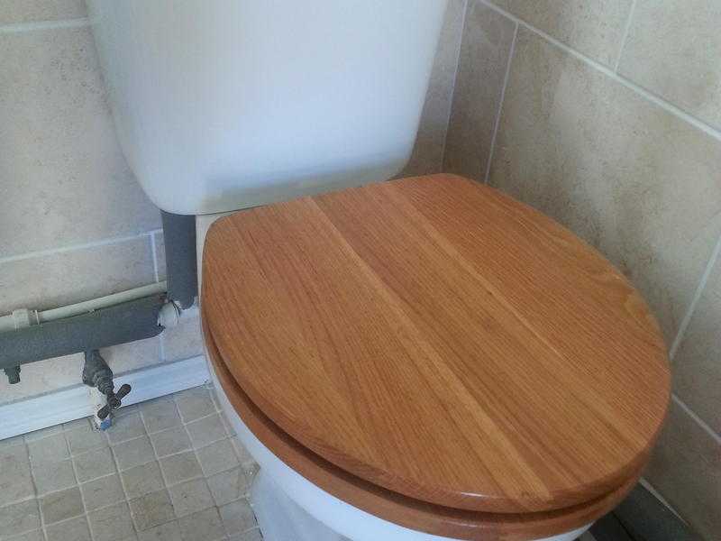 CLOSE-COUPLED TOILET WITH SLOW CLOSING WOODED SEAT.