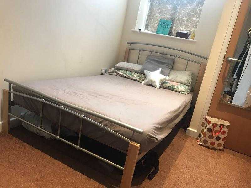 Metal frame double bed with mattress and pillows.